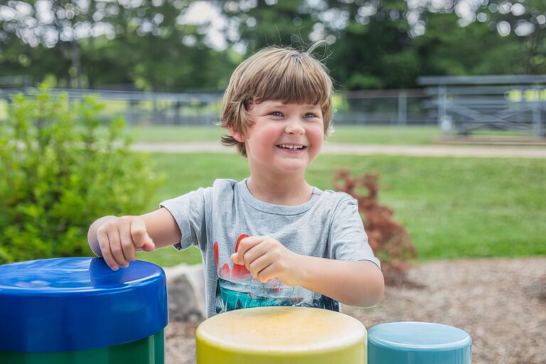 Young Boy Playing Percussion Tubes At Children's Music Park
